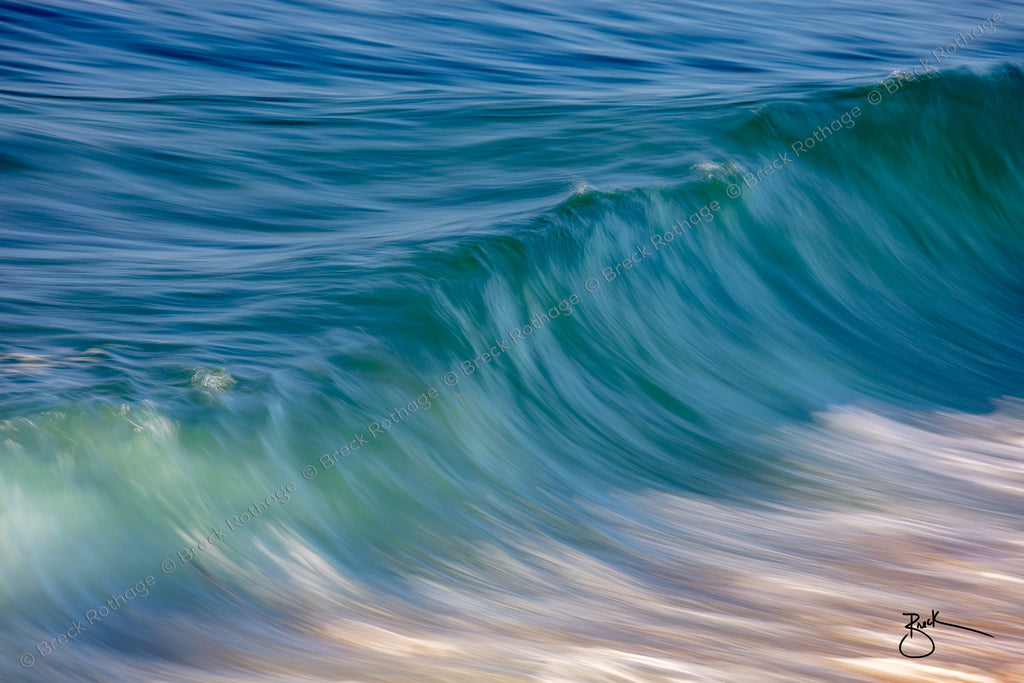 Gentle swells lazily roll toward the shore during a tranquil day at The Wedge in Newport Beach. Full of texture and variations of color as the sunlight glints upon the sea revealing jewel-like tones in emerald, aquamarine, turquoise, sapphire and even topaz from the sandy ocean bottom. Lazy shore days are what Simply Swell is made for. 