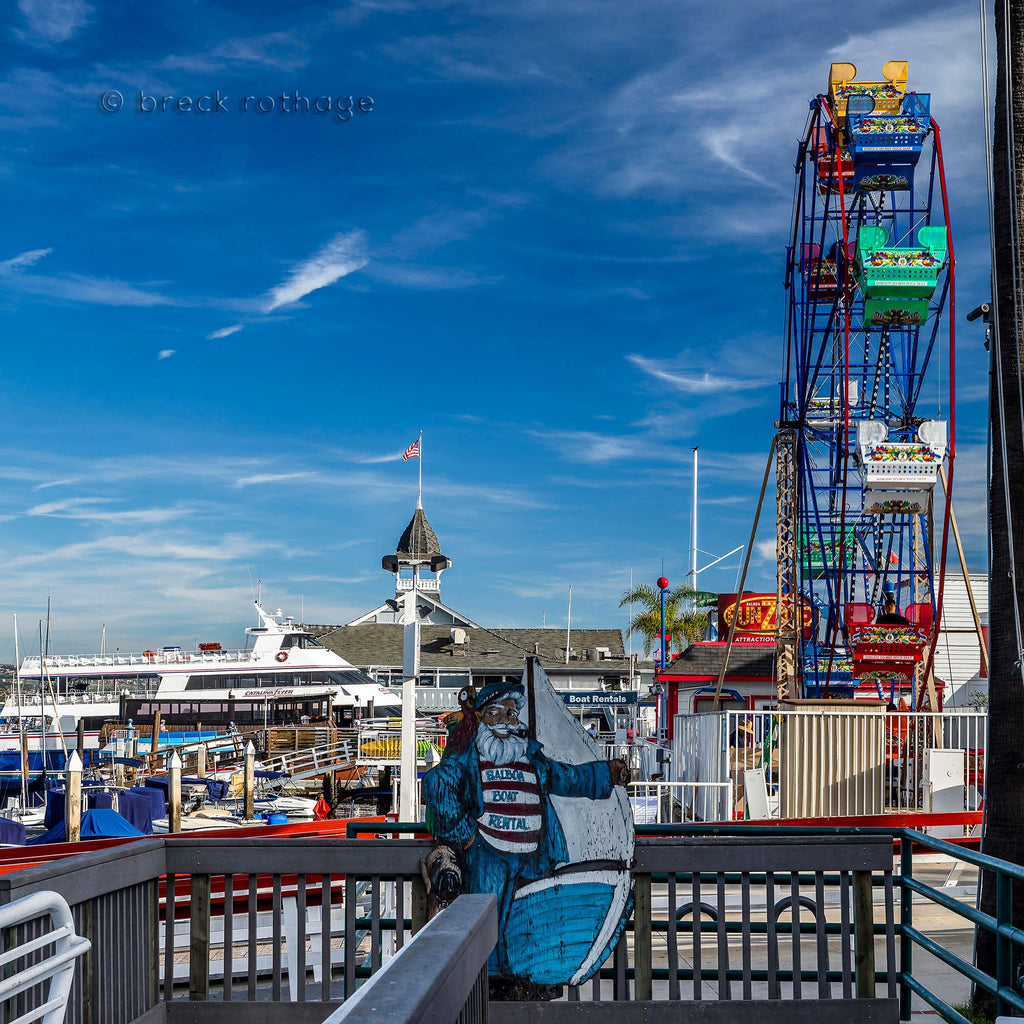 The Balboa Fun Zone - A fresh coat of paint on the ferris wheel buckets sweep up till you can almost touch the wispy clouds in the cerulean blue sky. 